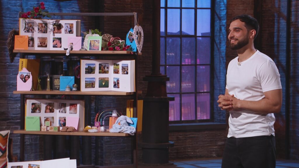 An image of Murad stood next to a display, with Mosaic Journals on show. 